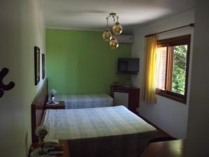 a green bedroom with a bed and a window at Hotel San Carlos in Carlos Barbosa