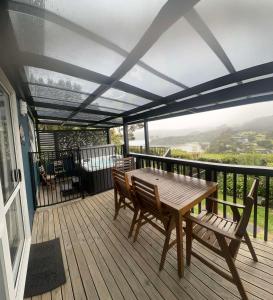a wooden deck with a wooden table and chairs at Coromandel Seaview Motel in Coromandel Town