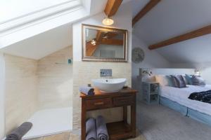 a bathroom with a sink and a bed and a mirror at Little Bream - pretty cosy cottage, sea views, walk to the beach in Mawnan Smith
