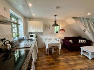 a kitchen and living room with a couch and a table at Little Bream - pretty cosy cottage, sea views, walk to the beach in Mawnan Smith