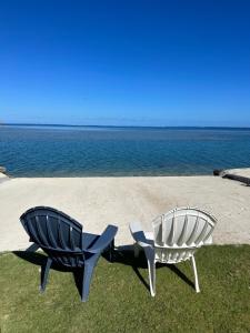 two chairs sitting on the grass next to the water at Maison entière Orama, plage privée in Torea