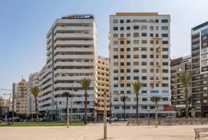 two tall buildings in a city with palm trees at Golden Sand Apartment - Terrace & OceanView 2BD in Tangier