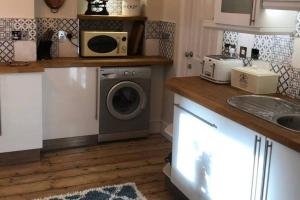 a kitchen with a washing machine and a microwave at Brooklyn Villa in Norwich