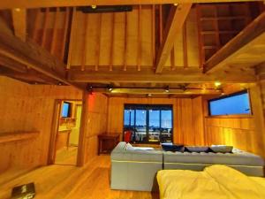 een woonkamer met een bank in een kamer met houten wanden bij マーレゲストハウス in Fukui