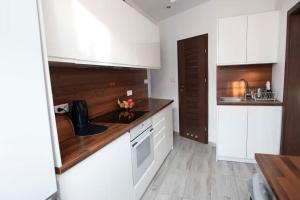 a kitchen with white cabinets and a wooden counter top at Apartament pod Katedra w Gnieznie in Gniezno +19 photos