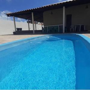 ein großer blauer Swimmingpool neben einem Haus in der Unterkunft Lugar encantador! in Jacumã