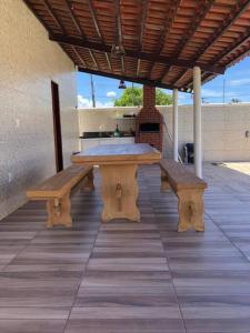 einen Picknicktisch und zwei Bänke auf einer Terrasse in der Unterkunft Lugar encantador! in Jacumã