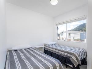 two beds in a white room with a window at Retreat by the Beach - Pauanui Holiday Home in Pauanui