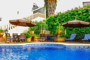 a swimming pool with chairs and tables and umbrellas at Hotel Hacienda Los Laureles in Oaxaca City