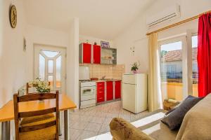 a kitchen with red cabinets and a table in a room at Apartment Kreso in Tkon