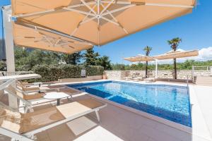 una piscina con sombrillas y sillas junto a una piscina en Apartments Tomo, en Novalja