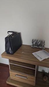 a black purse sitting on top of a wooden desk at Apartamento para aluguel de temporada, Barbacena in Barbacena