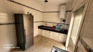 a kitchen with a refrigerator and a black counter at résidence bouylaghman in Monte ʼArrouit