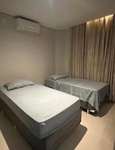 two twin beds in a room with a window at Quarto na Asa sul in Brasilia