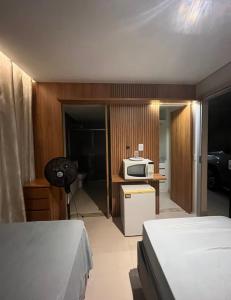 a bedroom with two beds and a kitchen with a microwave at Quarto na Asa sul in Brasilia