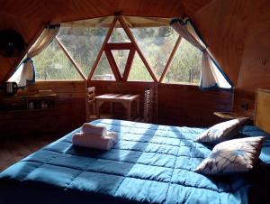 a large bed in a room with a large window at Puelo EnDomos in Lago Puelo