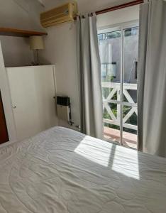 Un dormitorio con una cama blanca y una ventana. en Céntrico Duplex 4 personas, en Pinamar