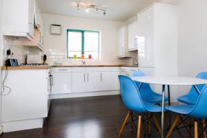 セント・オーステルにあるWheel Water Apartmentの白いキッチン(テーブル、青い椅子付)