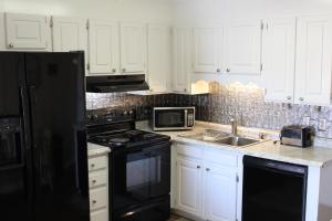 a kitchen with white cabinets and a black refrigerator at Sandy Shores in Myrtle Beach