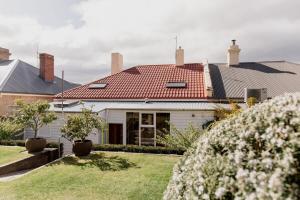 une maison blanche avec un toit rouge dans l'établissement 'Wietenah=' - Perfectly renovated historic cottage, à Hobart