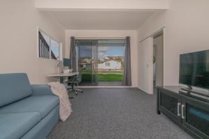a living room with a couch and a tv and a table at Across the Road to the Beach - Beach House in Whitianga