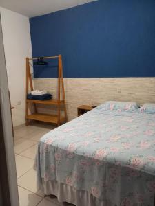 a bedroom with a bed and a blue wall at Pousada Ancoradouro in Cananéia