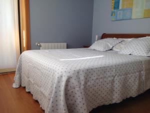 1 dormitorio con 1 cama con edredón blanco en Casa El Fontán, en Moaña