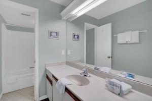 a white bathroom with a sink and a mirror at Wind Drift 501 by Vacation Homes Collection in Orange Beach