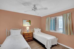 two beds in a bedroom with a ceiling fan at Wind Drift 501 by Vacation Homes Collection in Orange Beach
