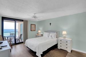 a white bedroom with a bed and a balcony at Wind Drift 501 by Vacation Homes Collection in Orange Beach