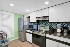 a kitchen with white cabinets and a stainless steel refrigerator at Wind Drift 114 North by Vacation Homes Collection in Orange Beach