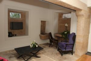 a living room with two chairs and a tv at Solar Do Castelo in Melgaço