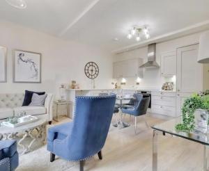 a living room and kitchen with blue chairs and a table at The Byron Suite in Lichfield