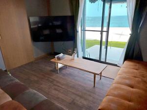 a living room with a couch and a tv and a table at Shima City Detached house SKO1 in Katada
