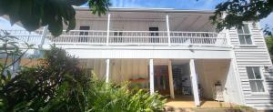 a white house with a balcony on top of it at Ribbonwood Bed & Breakfast, Emu Park Qld in Emu Park