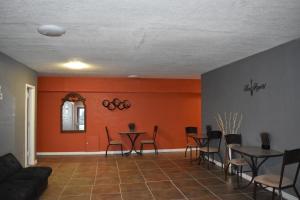 una sala de estar con paredes de color naranja, mesas y sillas. en Woodfield Inn and Suites, en Yoakum