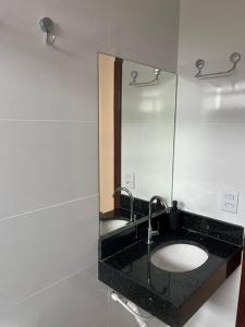 a bathroom with a sink and a mirror at Apartamento no Centro in Paracatu +15 photos