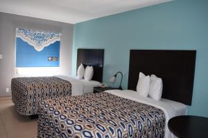 2 łóżka w pokoju hotelowym z niebieskimi ścianami w obiekcie Woodfield Inn and Suites w mieście Yoakum