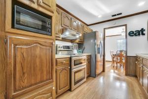 une cuisine avec des armoires en bois et un micro-ondes dans l'établissement Oaklawn Retreat - 4 Bedroom - Sleeps 10 - Fireplace, à Vernon