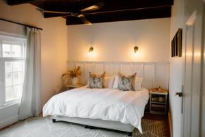 Un dormitorio con una cama con sábanas y almohadas blancas. en Melkhout Farm Cottage, en Bonnievale