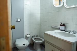 a white bathroom with a toilet and a sink at El diez 1 dorm con COCHERA in Córdoba