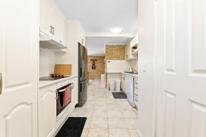 a kitchen with white cabinets and a hallway at 7 - 9 Mort Ave Dalmeny in Dalmeny