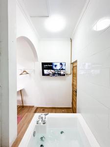 a bathroom with a tub and a tv on the wall at OsOs Paviliun in Yogyakarta +22 photos