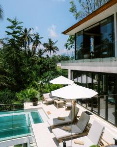 un patio con sillas y sombrillas junto a una piscina en Villa Joyia Ubud, en Ubud