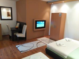 a room with a tv and a table and a bed at Apartments Leo in Trebinje