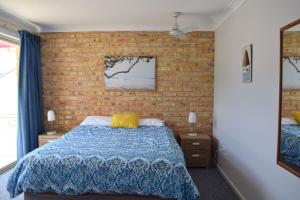 a bedroom with a bed and a brick wall at Ocean Shores 7 South West Rocks - Bring you own linen. in South West Rocks