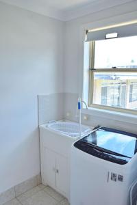 a washing machine in a bathroom with a window at Ocean Shores 7 South West Rocks - Bring you own linen. in South West Rocks +15 photos