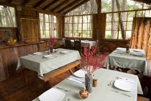 a dining room with two tables and chairs and windows at Inraki Lodge in Guaillabamba