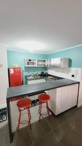 a kitchen with two red stools at a counter at Acogedor Departamento la Serena 3D 2B wifi estacionamiento céntrico in La Serena