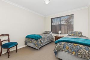 a bedroom with two beds and a chair and a window at The Dunsborough Drift Family Holiday Home in Dunsborough